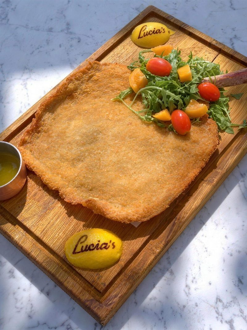 Veal milanese on a board with Lucia's lemons