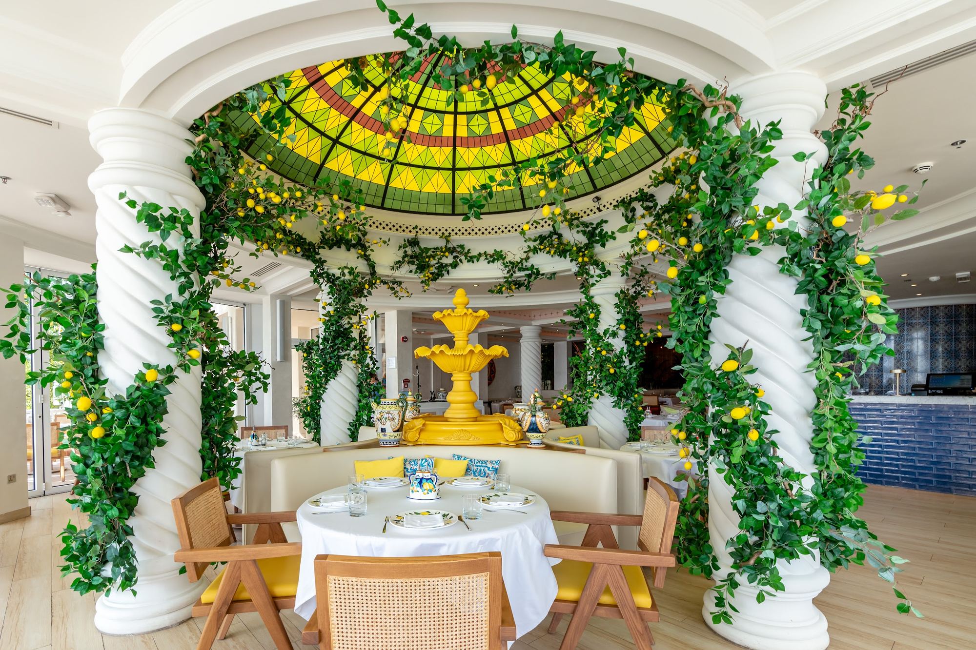 Lucia's Doha dining room: a lemon tree dome over a yellow fountain, white columns and blue majolica tiles